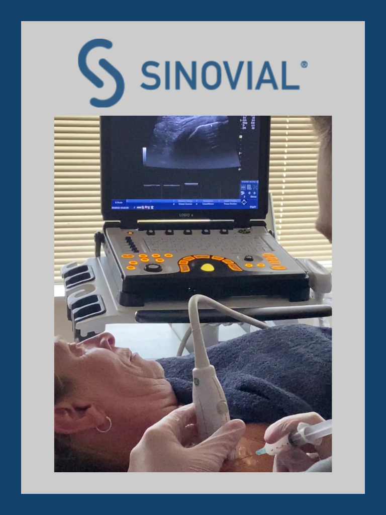 Photo of a lady lying with a practitioner putting an injection needle into her shoulder whilst both monitoring an ultrasound screen